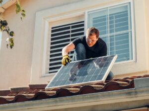man with gloves holding solar panels on the roof