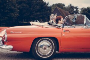 couple riding red ford thunderbird during daytime