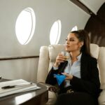 businesswoman holding a glass of whiskey while on a private jet