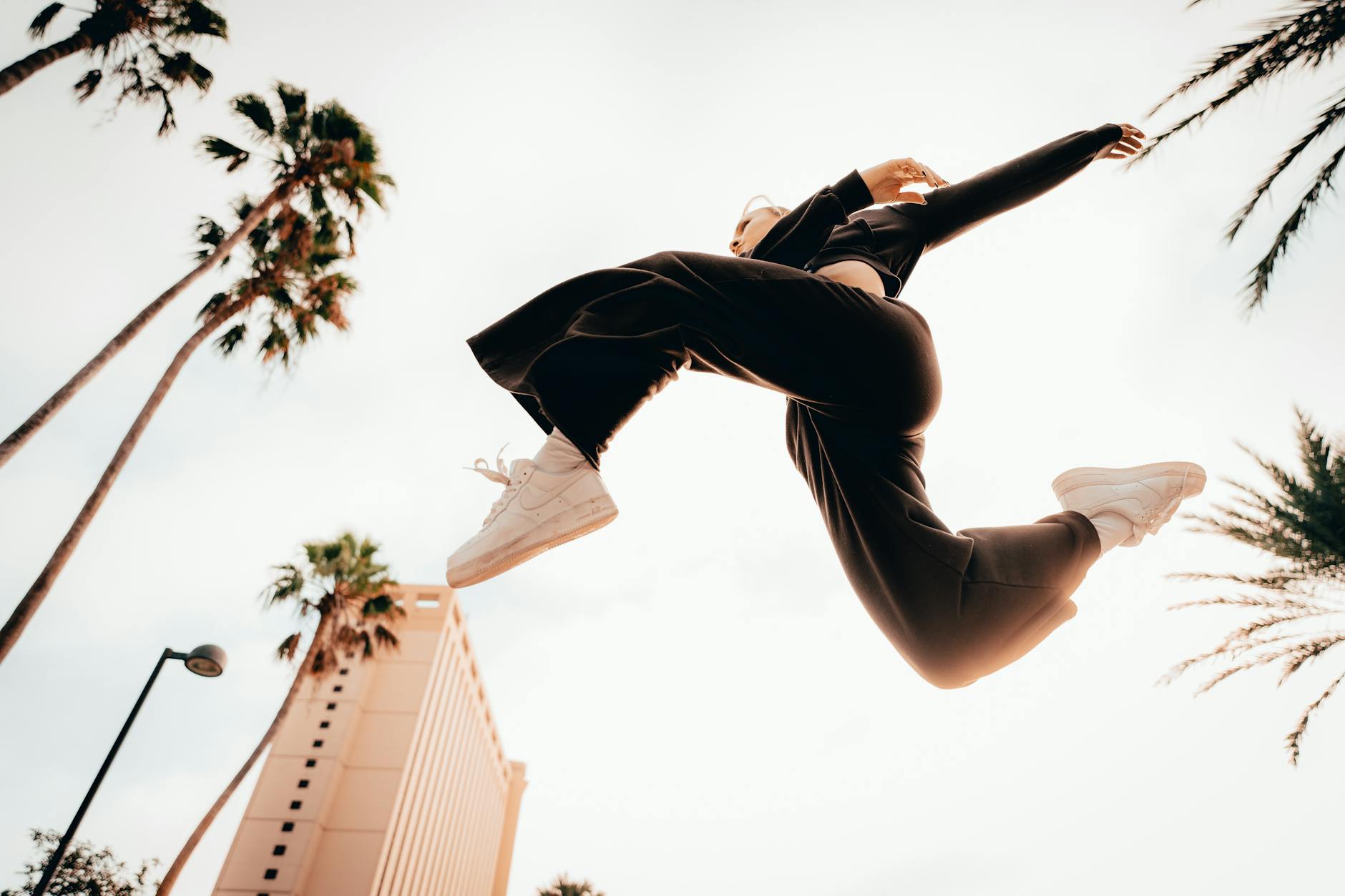 woman in sportswear jumping in air in tropical landscape
