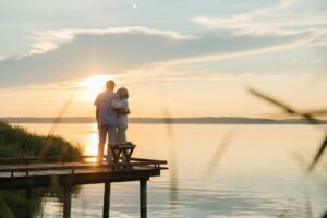 elderly couple standing on a wooden dock during dusk