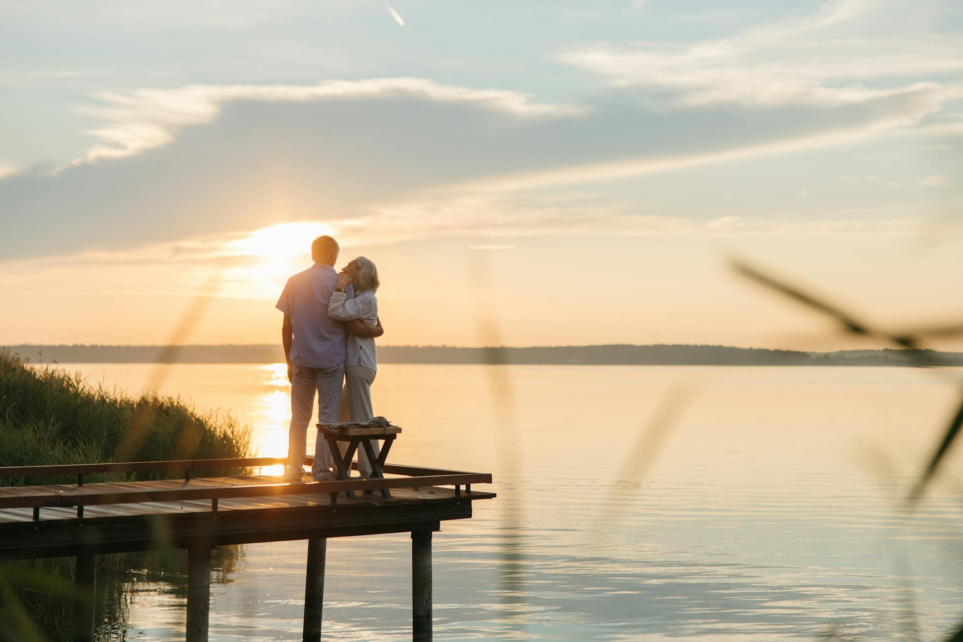 elderly couple standing on a wooden dock during dusk